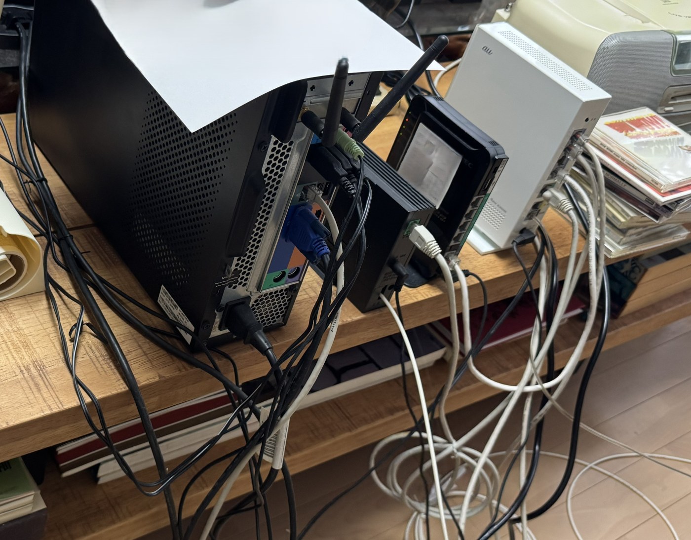作業前の机の裏。ルーターが2台あり、電源ケーブルとLANケーブルが絡み合っている