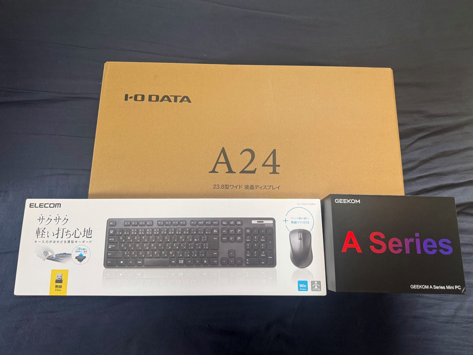 液晶モニター、ワイヤレスキーボードとマウス、ミニパソコンの箱が3つ並んでいる写真