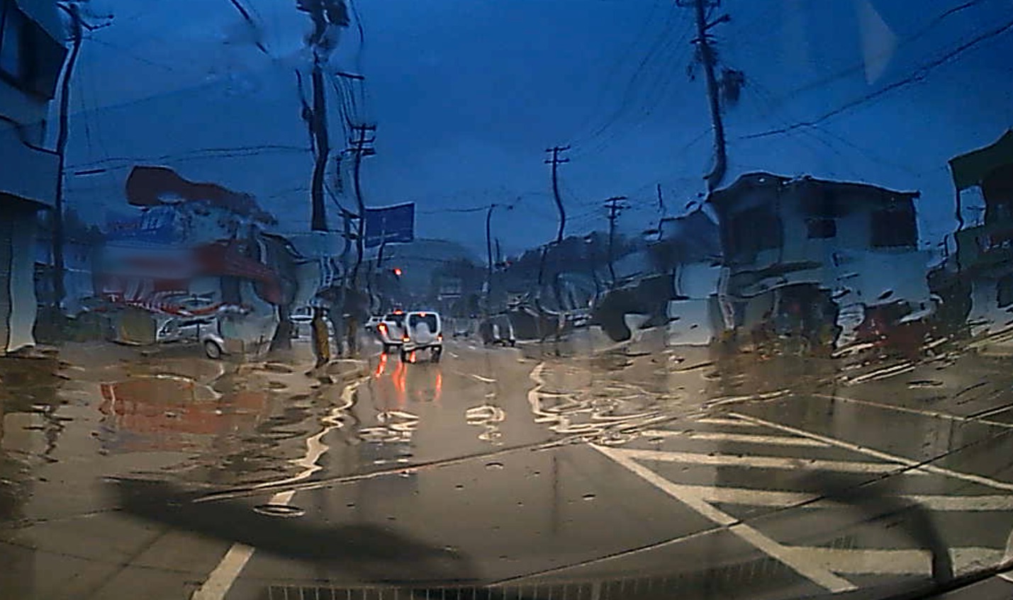 雨がフロントガラスに残り、電柱や建物が水で歪んで見えるドライブレコーダーの映像