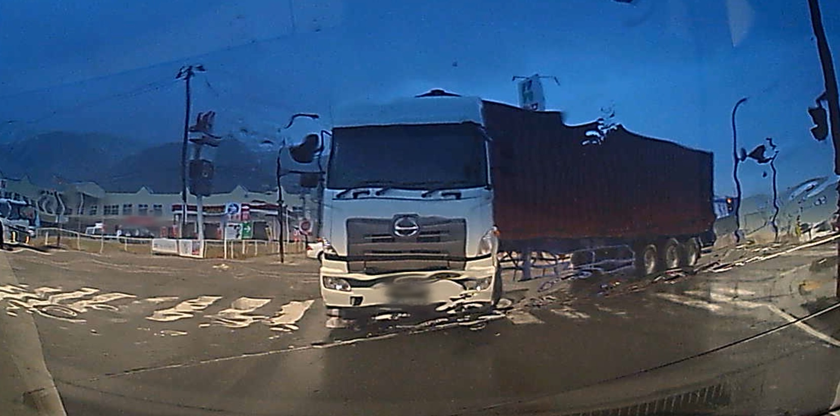 雨のフロントガラス越しに、信号待ちの前を右から大きく回り込んで曲がってくる大型トレーラーを撮ったドライブレコーダーの映像