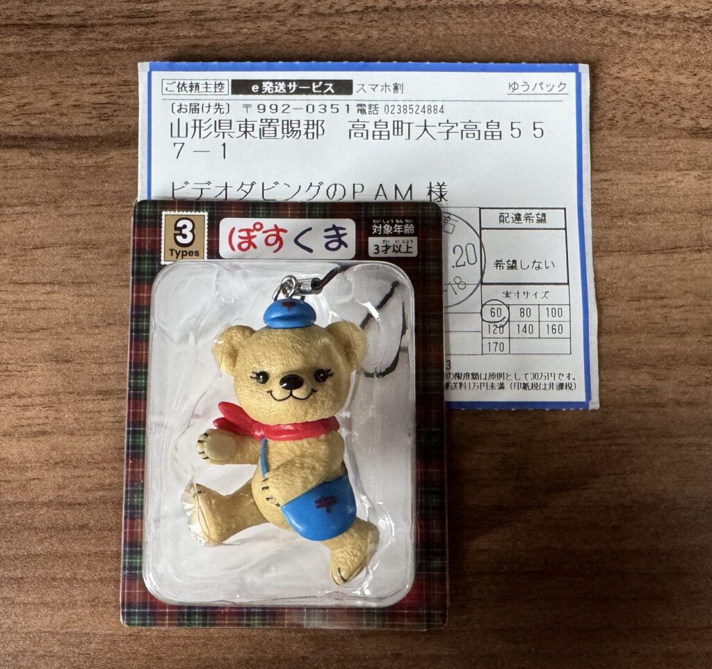 ゆうパックのご依頼主控と、ぽすくまのフィギュアストラップ。伝票にはスマホ割の表示と、実寸サイズ60に丸が付いている
