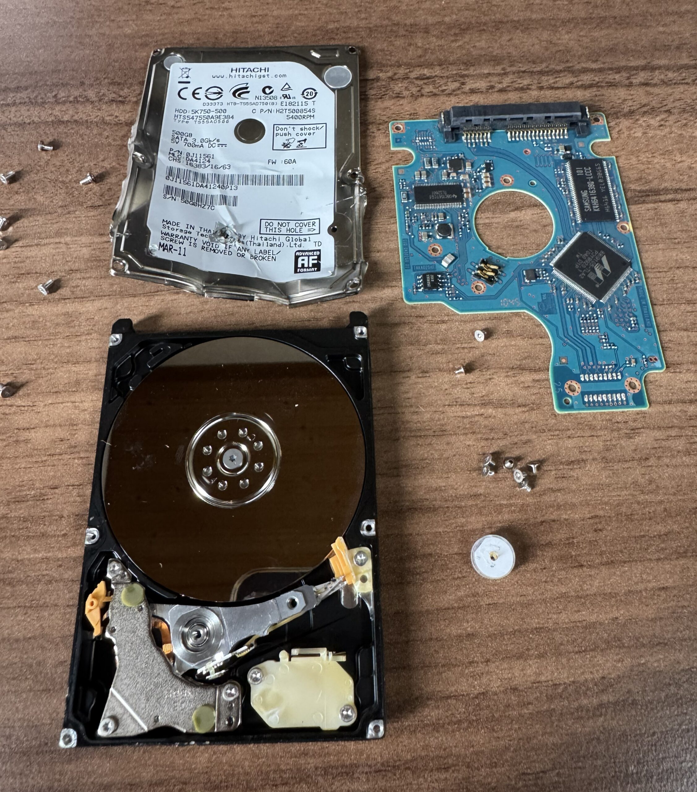 分解したノートパソコン用ハードディスク。ふた、基板、円盤の入った本体に分かれている