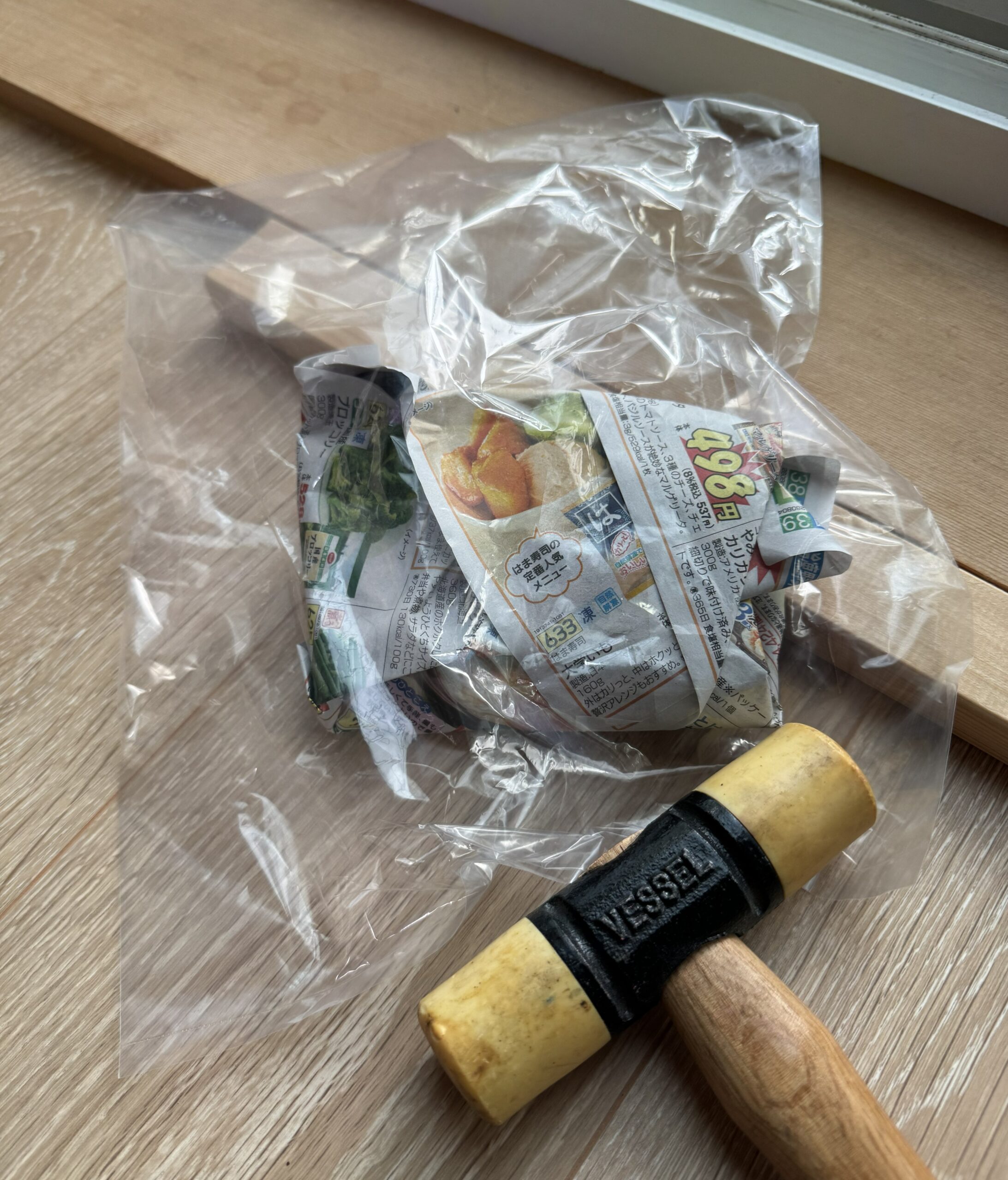 円盤をちらしで包み、さらにビニール袋に入れて、プラスチックハンマーを添えた飛散防止の準備