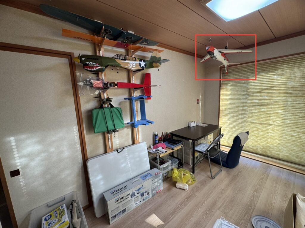 柱を2本に減らした現在の壁と作業机。天井から後退翼の機体を吊っている(赤枠)