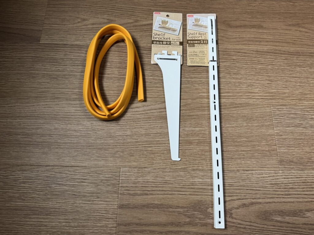ダイソーの壁面用棚受(約25cm)と壁面用棚受支柱(約50cm)、傷防止のオレンジのゴム
