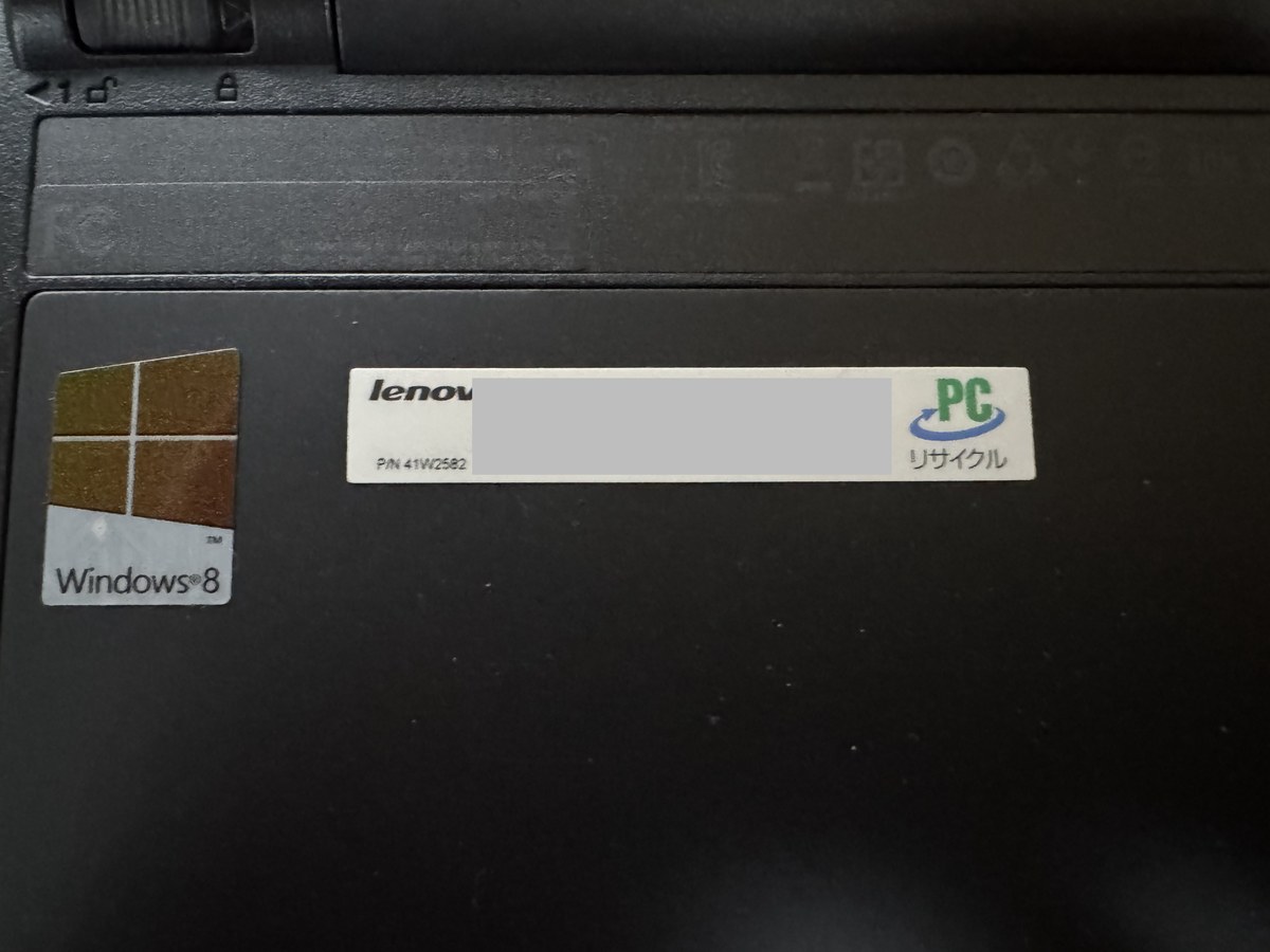 ThinkPad Edge E135の裏。左にWindows 8のシール、右にPCリサイクルマークの付いたレノボのシール(番号とバーコードは灰色で隠している)